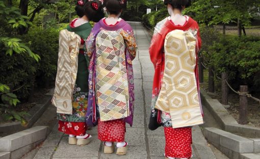 Three geishas weaing kimonos in a traditional street of Kyoto,Japan